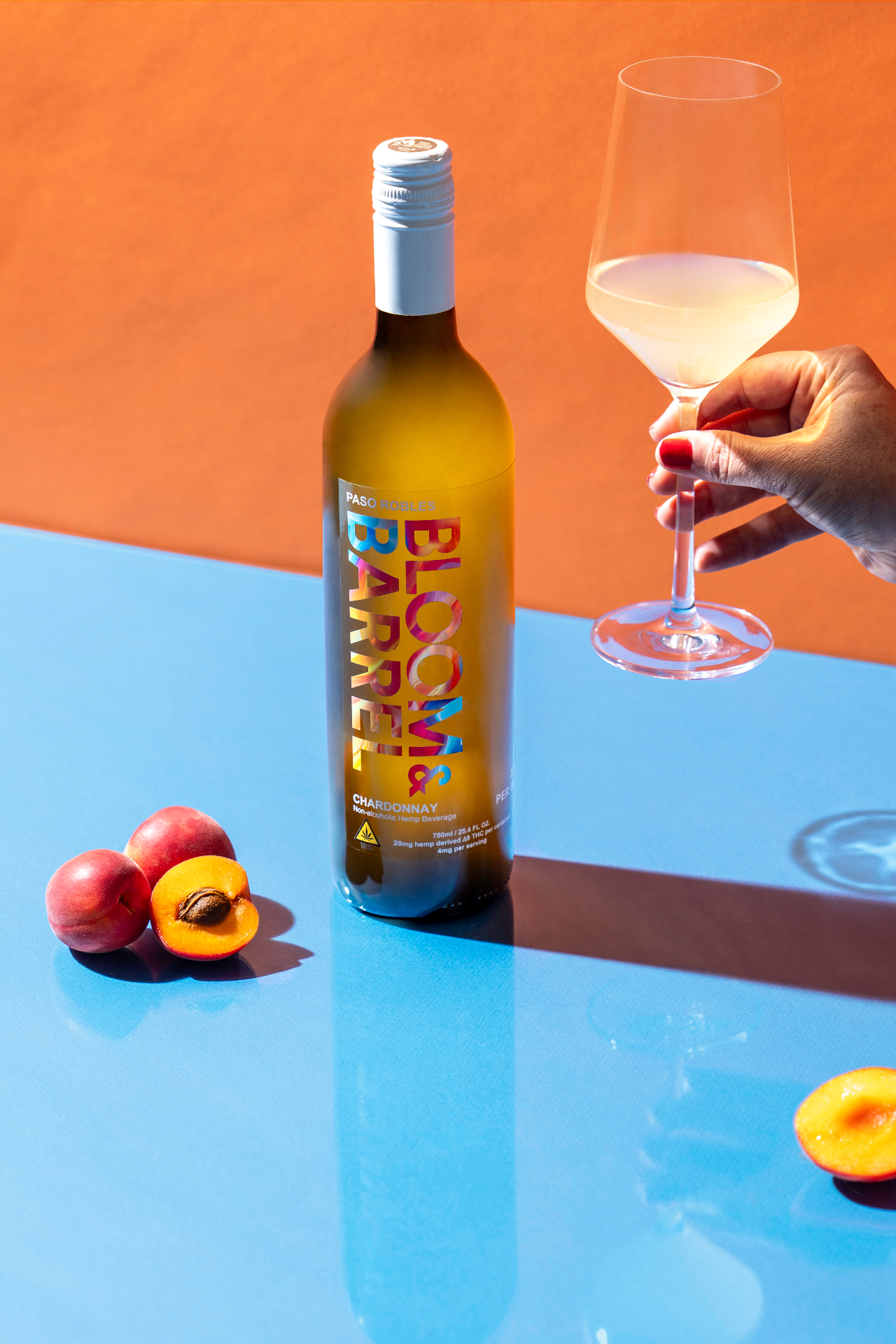 Bloom & Barrel Chardonnay bottle with a wine glass and fresh peaches